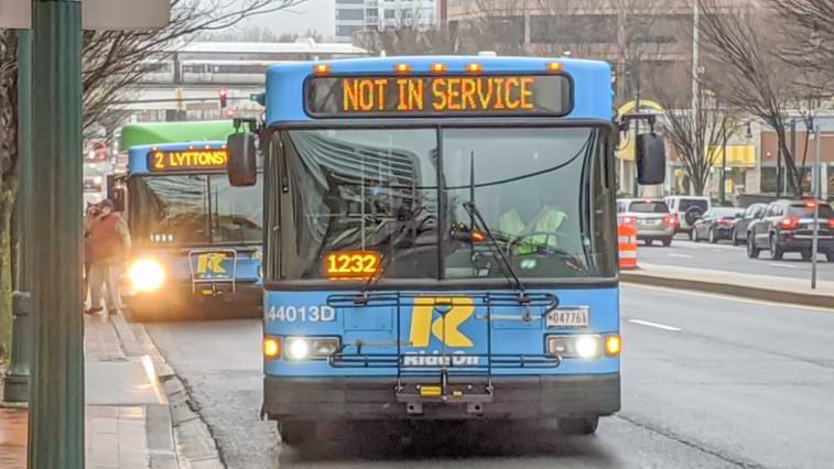 Two buses riding down the street in Maryland displaying not in service sign