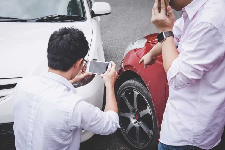 man taking a photo of the damage to cars after a car accident 