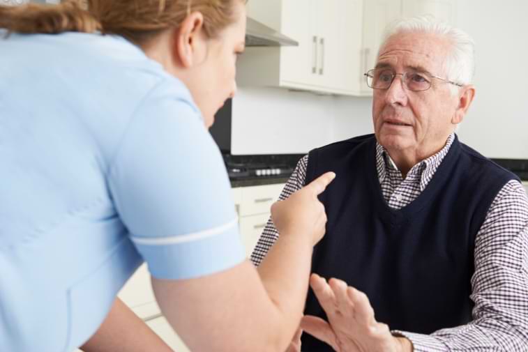 Elderly man putting a hand up to stop nursing home abuse from care worker 