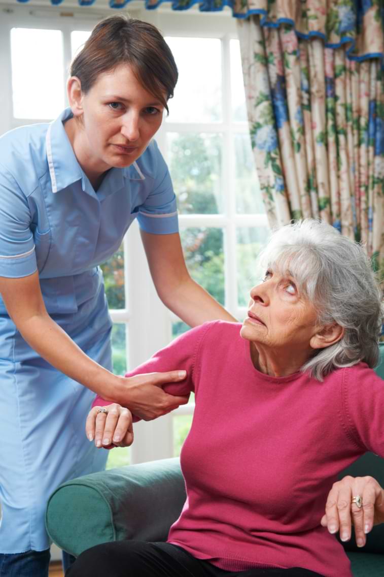 Elderly woman deals with nursing home abuse as care worker forcefully grabs her arm to remove her out of seat 