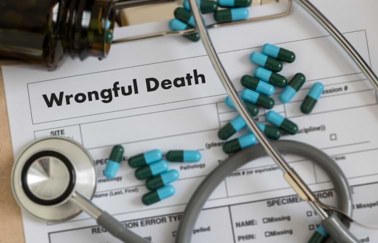 Wrongful death claim form on desk with medication pills and stethoscope on top of form 